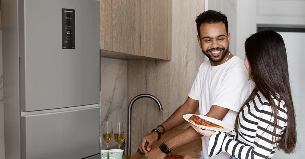 Casal preparando refeição em cozinha planejada.
